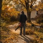 Jardinier utilisant un souffleur à feuilles dans un jardin en automne
